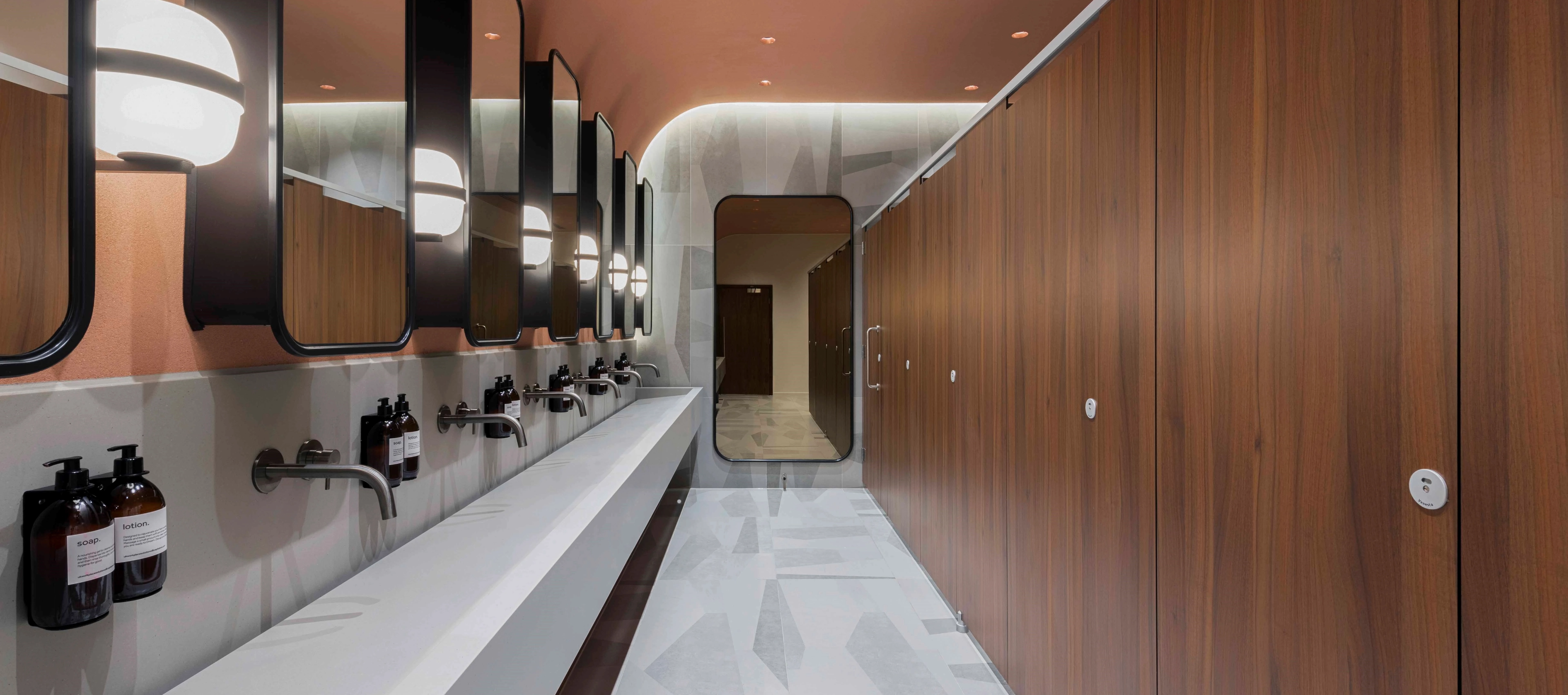 Walnut-panelled washroom with backlit mirrors